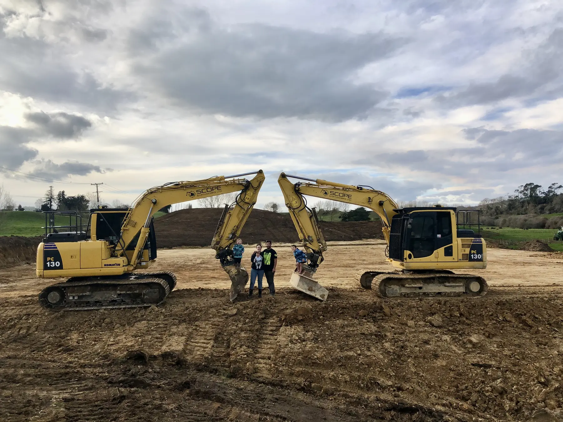 Two Scope Earthworks excavators with booms raised over the crew on site